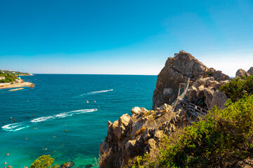 Panoramic view of the big rock in the sea with a stretched suspension bridge on the mountain in...