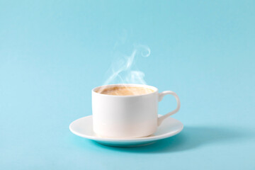 Steaming coffee cup on pastel blue background. White сoffee cup with steam. Front view, copy space
