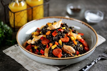 Black risotto with cuttlefish ink, chicken, chorizo sausages and vegetables.