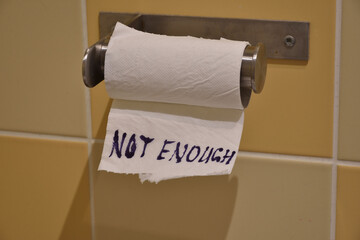 Toilet paper shortage concept. Not enough. Text on toilet paper - 383120345