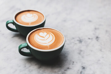 Two beautiful cups of cappuccino or latte on the table. Cosy coffee break concept. Flat-lay, top view. Copy space for your text.