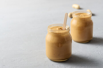 Homemade peanut butter in glass jars on concrete surface.