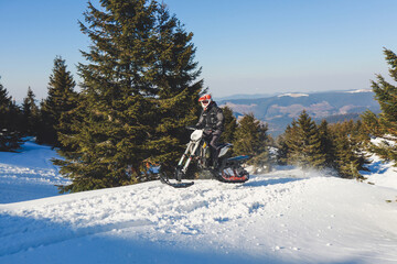Snowbike rider in mountain valley in beautiful snow powder. Snowdirt bike with splashes and trail. Snowmobile winter sport riding