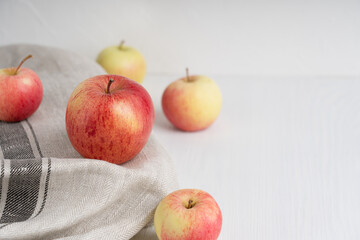 Group of organic tasty red and yellow apples on textile towel on white wooden background showing healthy lifestyle and vegetarian dietary eating. Image with copy space, horizontal orientation
