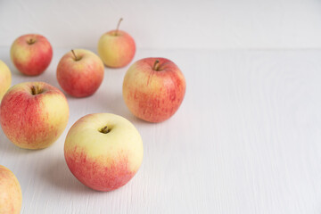 Group of organic tasty red and yellow apples on simple white wooden background at kitchen showing healthy lifestyle and vegetarian dietary eating. Image with copy space, horizontal orientation