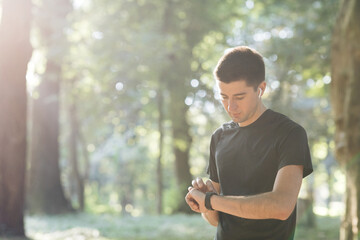 Man runner using smart watch. Handsome guy tracking result after workout. Portrait of fitness man checking result. Sport man looking smart watch