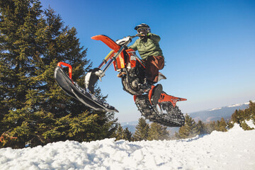 Snowbike rider in mountain valley in beautiful snow powder. Snowdirt bike with splashes and trail....