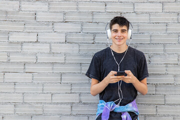 teenager boy with mobile phone and headphones on the wall