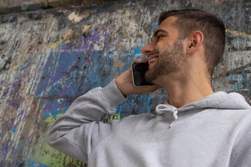 portrait of young man with mobile phone on the street, stains or paint chips on the wall without intellectual property