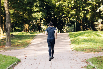 Adult man in sportswear jogging on the park in early morning. Sports people. Sportsman. Running activity. Healthy lifestyle