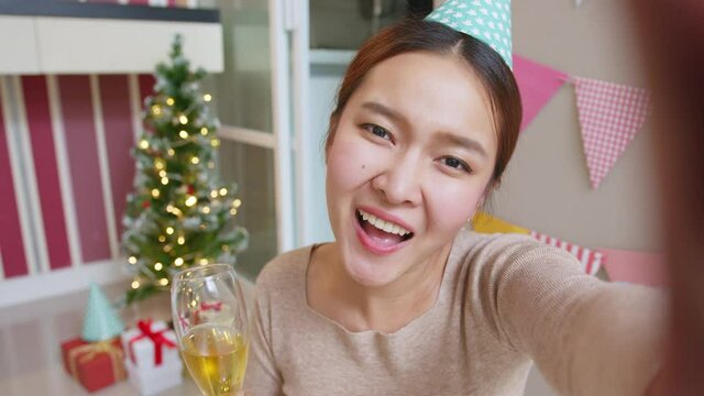 POV Asian woman holding wine glass to celebrate a party via video call conference, new normal for birthday Christmas and new year party at home