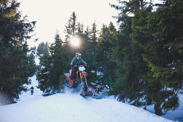 Snowbike rider in mountain valley in beautiful snow powder. Snowdirt bike with splashes and trail. Snowmobile winter sport riding