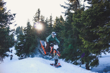 Snowbike rider in mountain valley in beautiful snow powder. Snowdirt bike with splashes and trail. Snowmobile winter sport riding