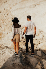 Loving pair walking on a rocky mountain, enjoying beautiful mountain landscape. They holding hands.