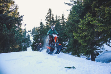 Snowbike rider in mountain valley in beautiful snow powder. Snowdirt bike with splashes and trail. Snowmobile winter sport riding