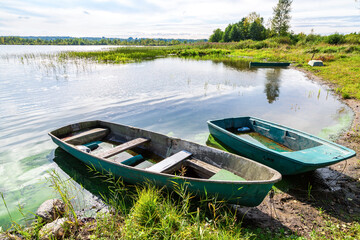 Plastic fishing boats on the bank of the lake in summer