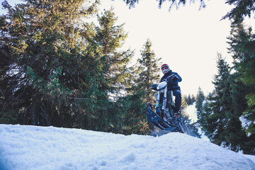 Snowbike rider in mountain valley in beautiful snow powder. Snowdirt bike with splashes and trail. Snowmobile winter sport riding