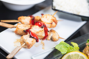 Traditional, oriental and Asian kebabs on a wooden skewer of grilled chicken pieces boiled rice as a garnish.