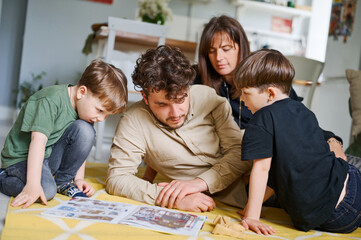 Young father reading book with children at home. Happy family spending time on the floor