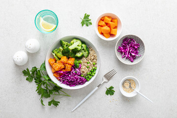 Vegetarian quinoa and broccoli lunch Buddha bowl with baked butternut squash or pumpkin, green peas and red cabbage, top down view