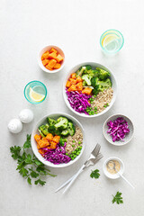 Vegetarian quinoa and broccoli lunch Buddha bowl with baked butternut squash or pumpkin, green peas and red cabbage, top down view