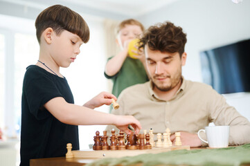 Father teaching son how to play chess. Concept of education and teaching.