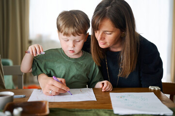 Happy family. Mother with little son painting and drawing together. Caucasian boy with his mother studying at home