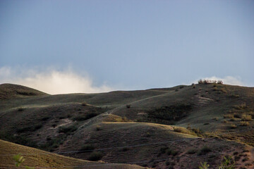 Scenery of green naked hills under the blue evening sky