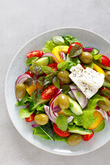 Greek salad. Fresh vegetable salad of cucumbers, tomatoes, olives, onion, bell pepper, feta cheese, lettuce and herbs and dressed with salt, pepper and olive oil. Horiatiki salad