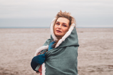 Woman in costume with cape. adult woman with a mantle standing on the seashore