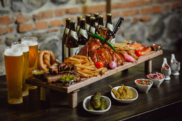 Meat set with beer in a restaurant. Fried veal shank with beer and chips.