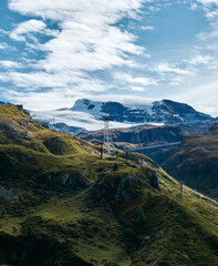 path to eternal ice and peaks from grassy slopes against a cloudy sky