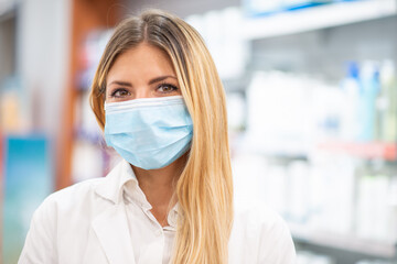Smiling pharmacist wearing covid coronavirus mask in her pharmacy