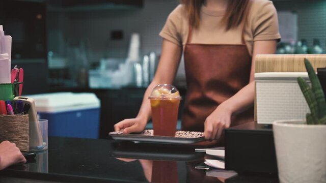 Close up woman using mobile scan QR or NFC payment on smartphone paying for her lemon ice tea in cafe