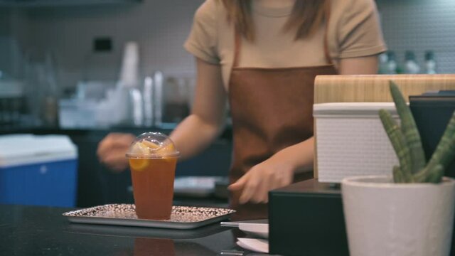 Close up woman using mobile scan QR or NFC payment on smartphone paying for her lemon ice tea in cafe