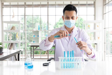 scientist man wearing medical face mask doing or testing a chemical experiment in laboratory