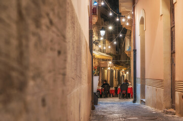 Kleines gemütliches Restaurant in einer Seitenstraße in Ortygia mit romantischer Beleuchtung bei...