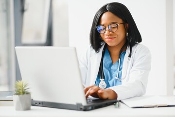 Young African-American doctor working on laptop in clinic