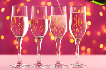 Four champagne glasses against pink background with blurred garland