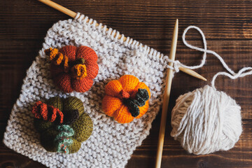 Obraz na płótnie Canvas Knitting pumpkins on wood background, top view. Cosy home background
