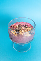 Mixed Berry Acai Smoothie Bowl on a light blue background. With granola, raisins and pink coconut chips. Copy space.