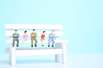 White bench with miniature people on blue background