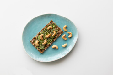 cracker with pesto and nuts on a plate