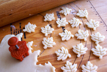 Cut-Out Pastry Dough Leaves for a Pie and a Wooden Pastry Board with a Wooden Rolling Pin and Leaf Mini Leaf Cookie Cutter