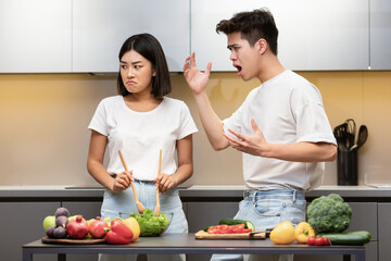 Asian Husband Shouting At Wife While She Cooking In Kitchen