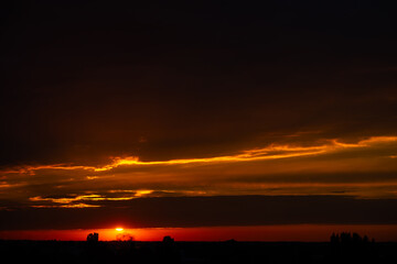 Heavy cloudy sky at sunset. Orange line of light between black clouds. A landscape of beautiful...