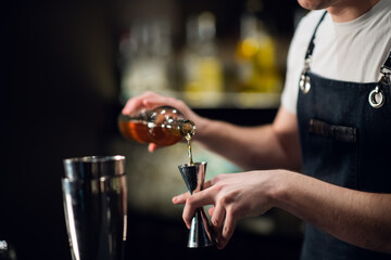 Close-up of the process of preparing a cocktail with liqueur at a party of friends in a nightclub. The dark blurred background