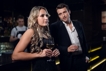 charming girl and handsome man with cocktail glasses in a nightclub.