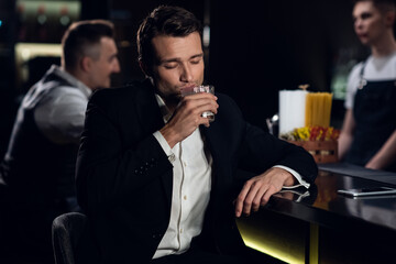 a beautiful man poses for a photo at the bar of a restaurant with a cocktail in his hands, portrait.