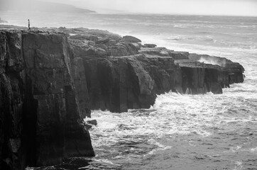 Black and white seascape of Irish cliffs battered by waves, Ireland